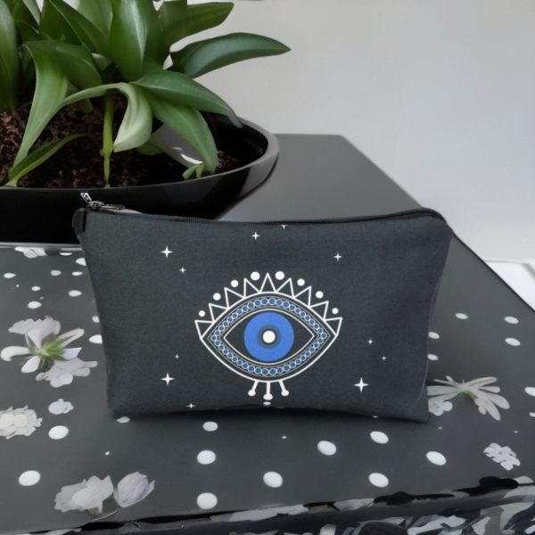 A black star bag with blue evil eye styling sitting on a black top.