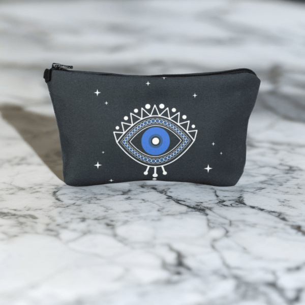 A black star bag with blue evil eye styling sitting on a marble top.