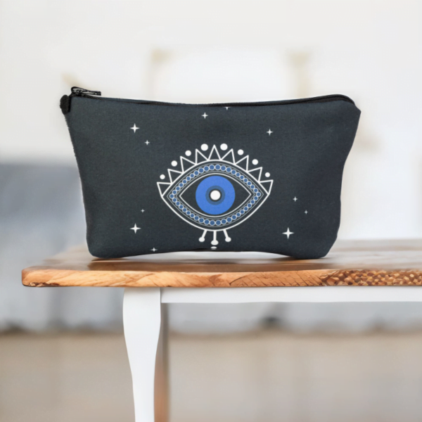 A black star bag with blue evil eye styling sitting on a table.
