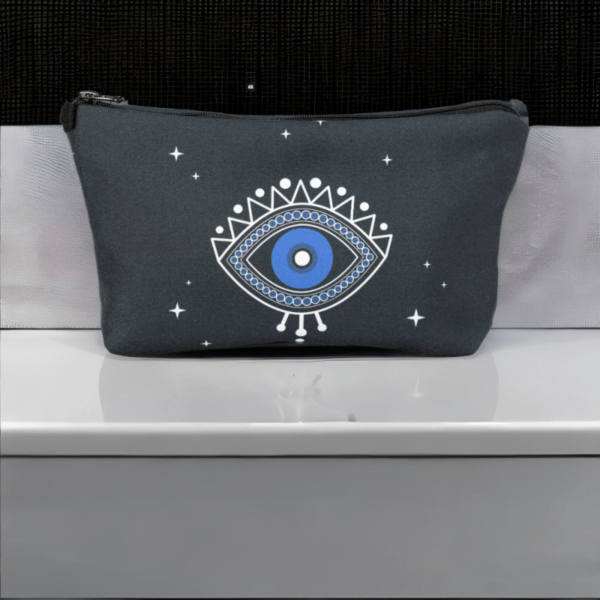 A black star bag with blue evil eye styling sitting on a silver top.
