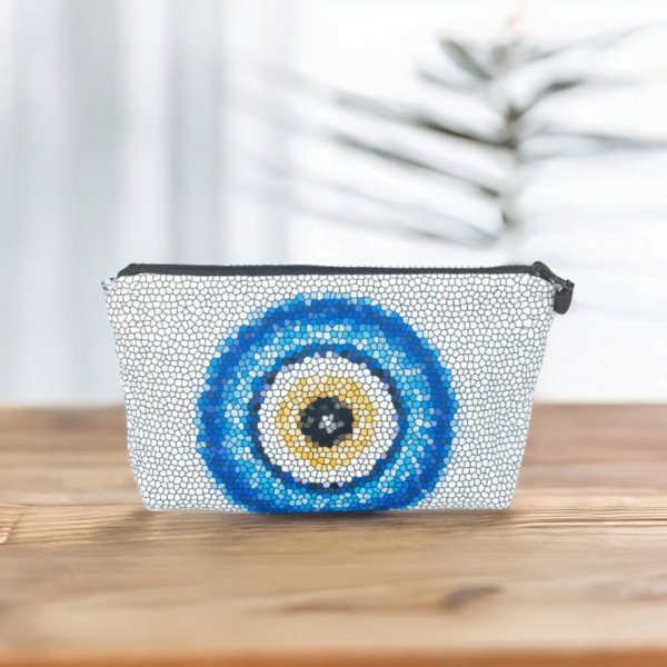 The Nadine bag, a white mosaic patterned cosmetic bag adorned with large blue and yellow evil eye motif in the centre
