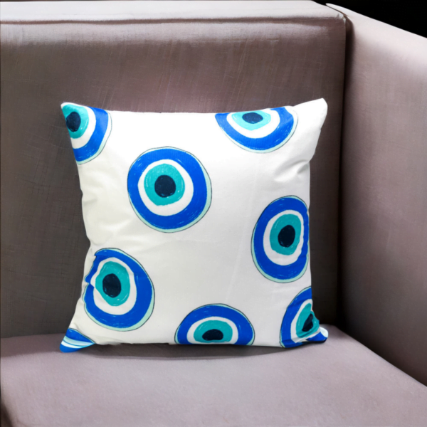 Malda Cushion, a white and plump cushion adorned with blue and white evil eye imagery on a chair.