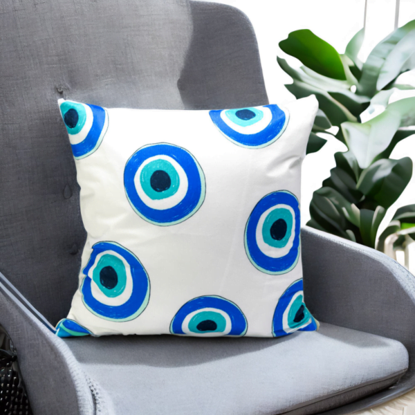 Malda Cushion, a white and plump cushion adorned with evil eye imagery on a chair.