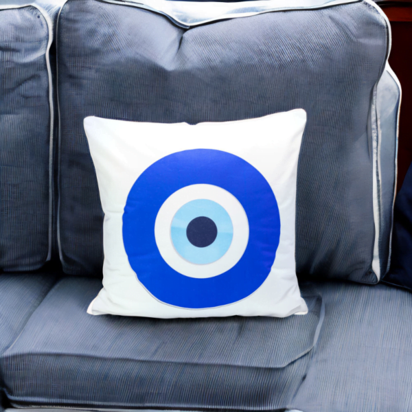 the hiba cushion, a white and plump cushion adorned with artistic blue and white evil eye imagery on a slate sofa.