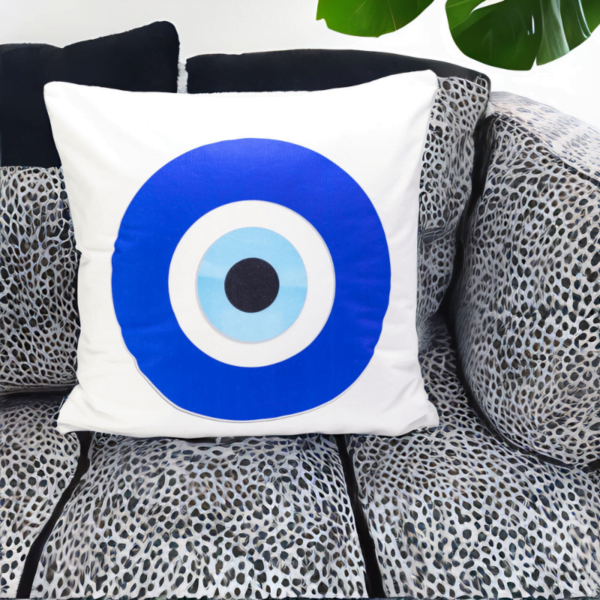 the hiba cushion, a white and plump cushion adorned with artistic blue and white evil eye imagery on a leopard print couch.