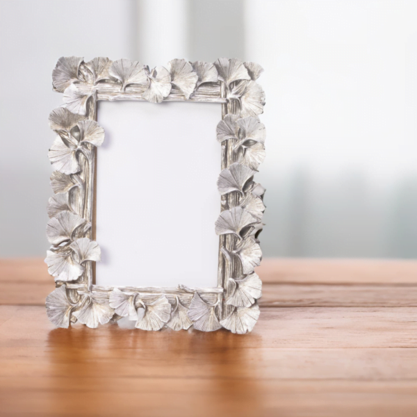 A silver ginkgo leaf portrait frame on a wood coffee table