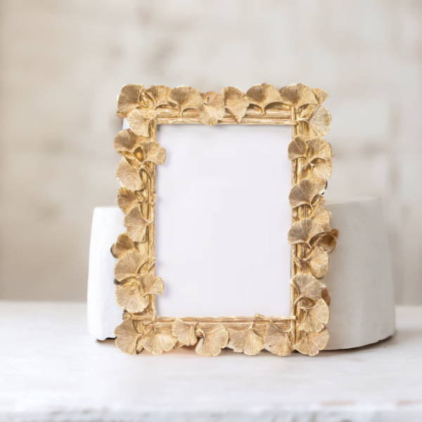 A Laura Gold Portrait Frame on top of a marble table.