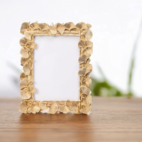 A gold frame on wooden table adorned with delicate leaves, adding an elegant touch to any artwork or photograph.