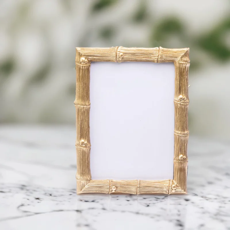 A gold bamboo wedding photo frame on a marble top.