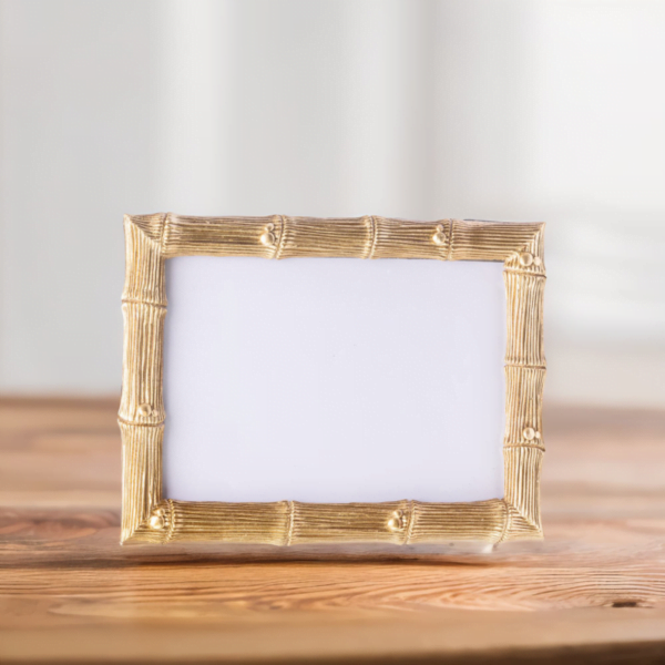 A gold bamboo wedding photo frame on a wooden top.