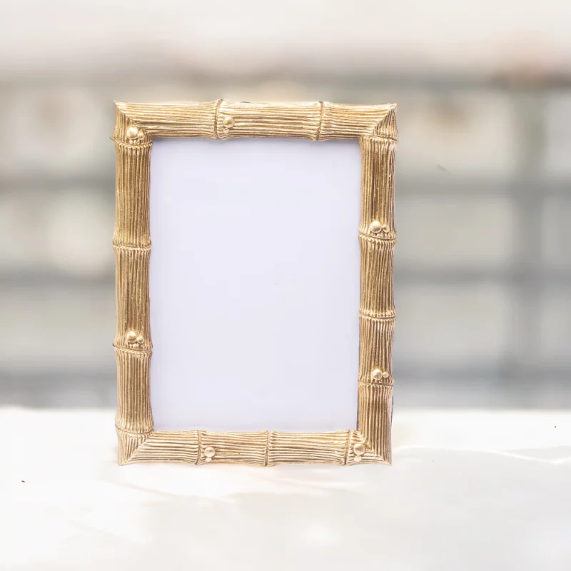 A gold bamboo wedding photo frame on a marble top.