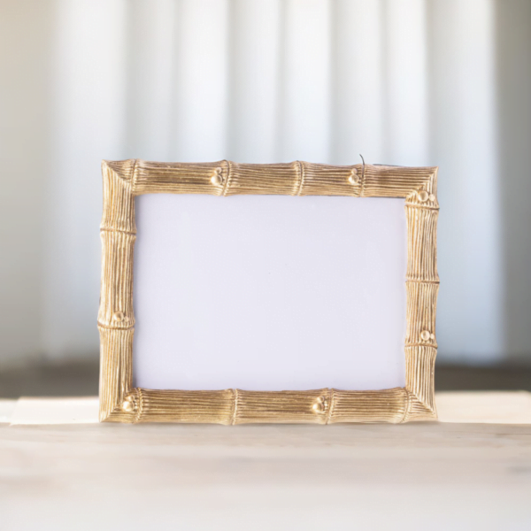 A gold bamboo wedding photo frame on a wooden table.