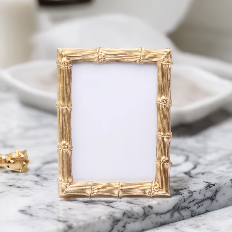 A gold bamboo wedding photo frame on a marble top.