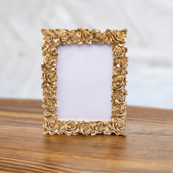 A gold rose portrait photo frame on wooden table.