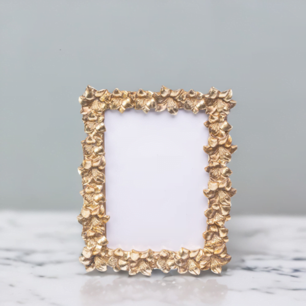 A handmade gold photo frame with leaf designs, placed on a marble table in London.
