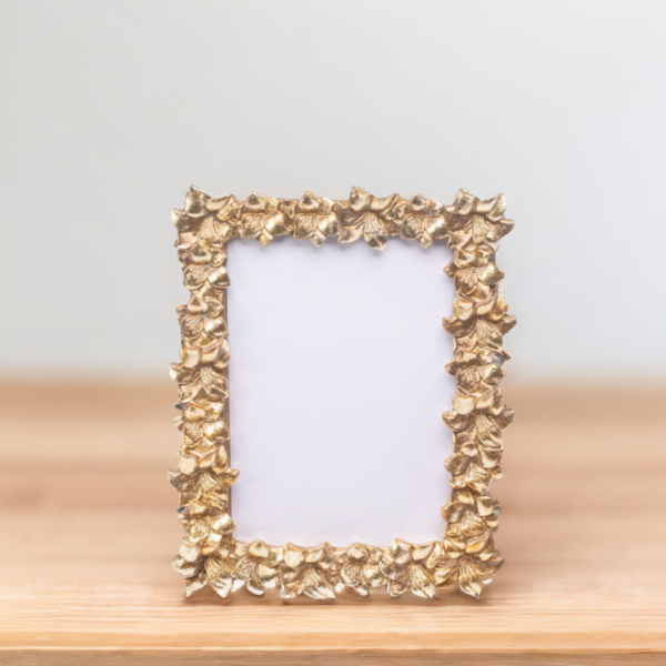 A gold frame on wooden table adorned with luxury leaves, adding an elegant touch to any artwork or photograph.