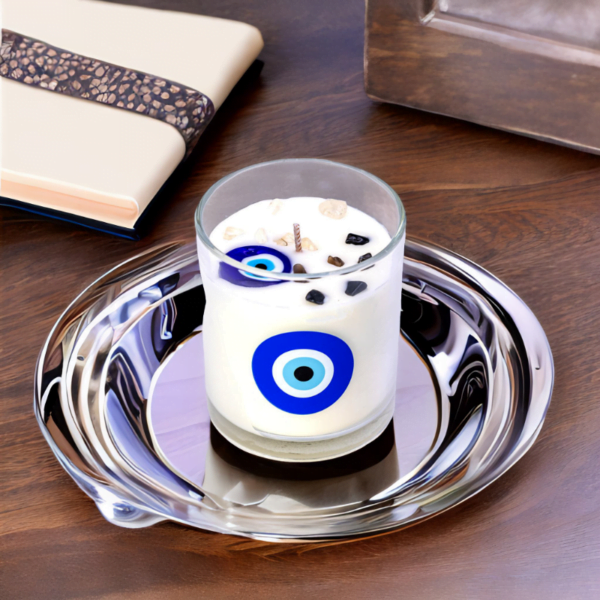 An Evil Eye Cotton Flower Candle in a glass on a plate.