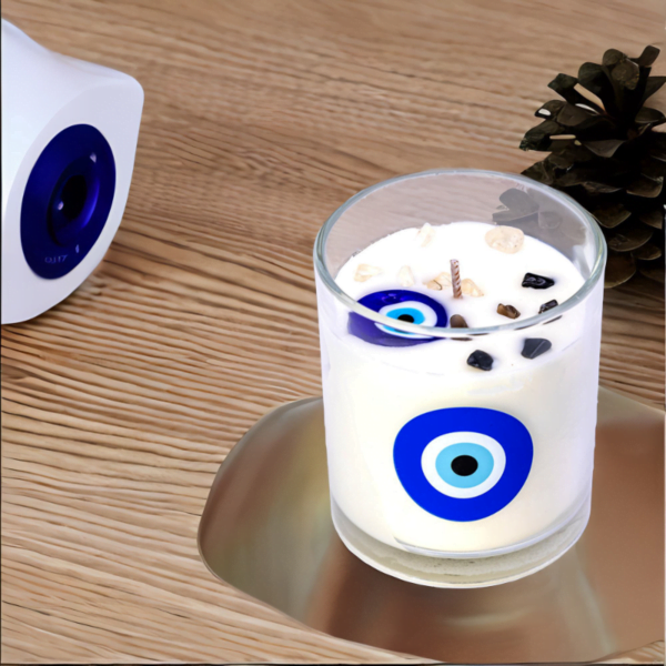 An Evil Eye Lavender Amber Luxury Candle with an evil eye on it next to a pine cone.
