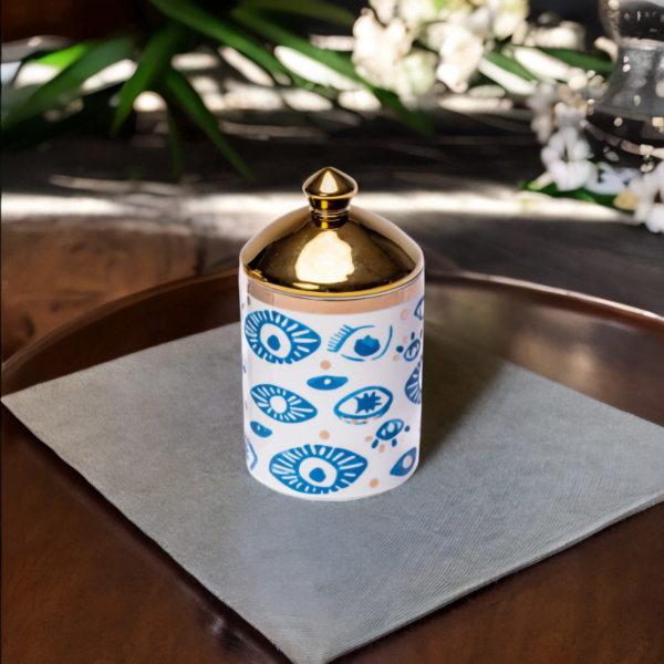 An Evil Eye Canister with a gold lid on a table.