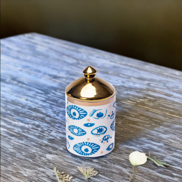 An Evil Eye, blue and white with gold accents Decorative Canister on a wooden table.