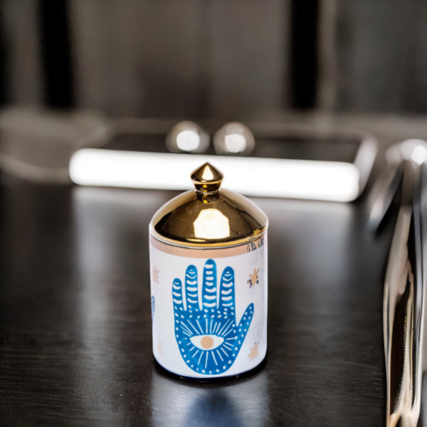 a blue and white porcelain canister with gold lid and Hamsa hand styling on kitchen table.