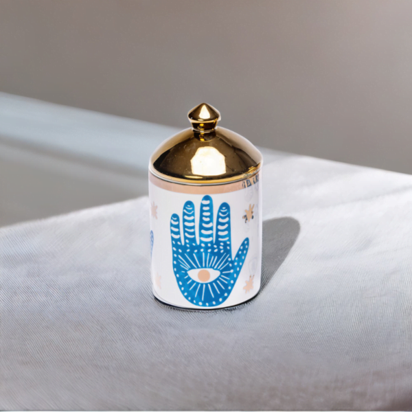 a blue and white porcelain canister with gold lid and Hamsa hand styling.