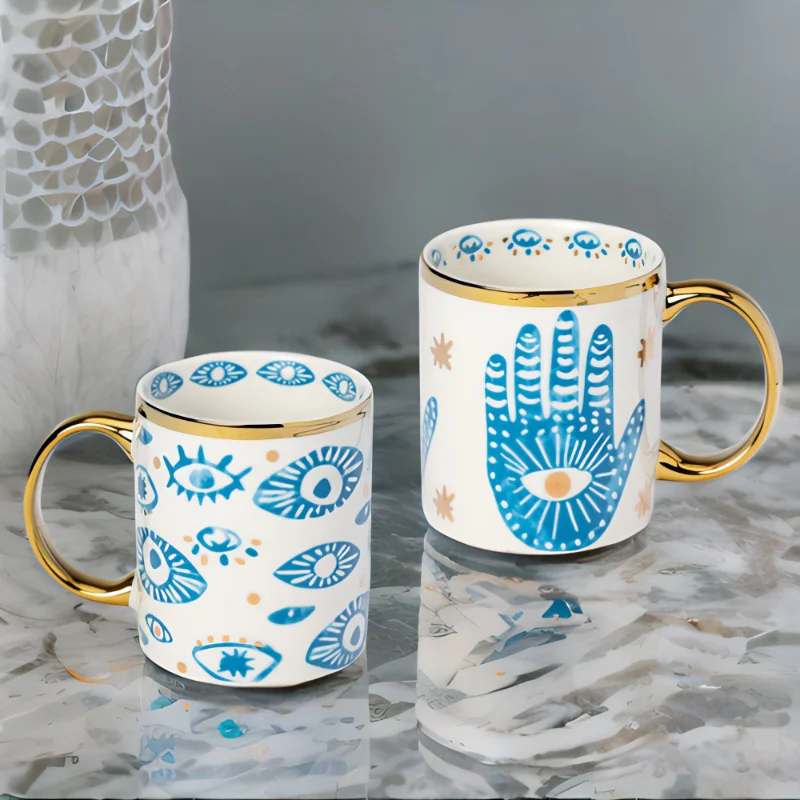 Hamsa Hand and Evil Eye mugs on a marble top.