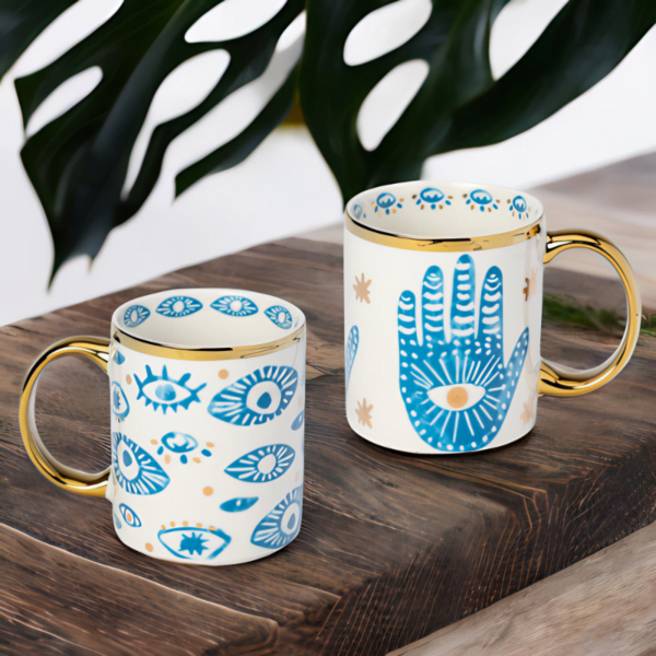 Hamsa Hand and Evil Eye mugs on a wooden table.
