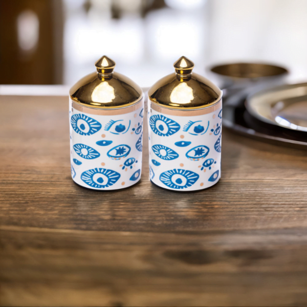 Two Evil Eye Canisters (Set of 2) with gold lids on a wooden table in London.