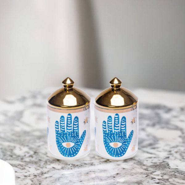 A porcelain set of two matching canisters with hamsa hand styling.