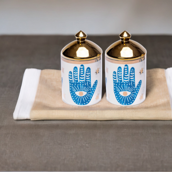 A porcelain set of two storage canisters with hamsa hand styling.