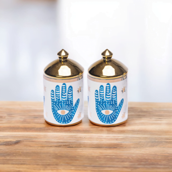 A porcelain set of two decorative canisters with hamsa hand styling.