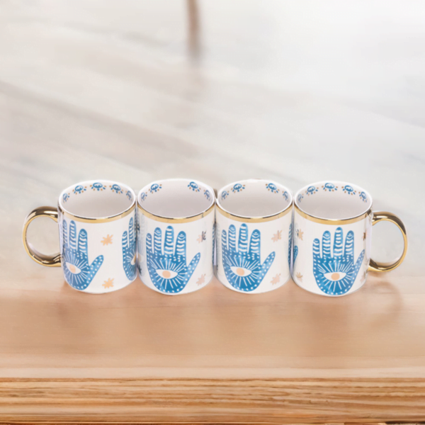 4 matching Hamsa hand mugs on wooden top.