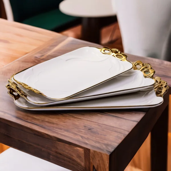 Three flat ceramic serving plates on a wooden table.