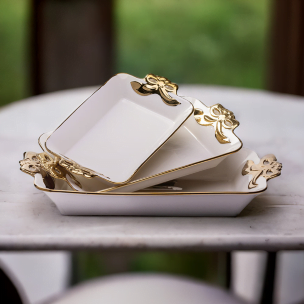 a set of three Deep Serving Ceramic dish with gold trim sits on top of a table.