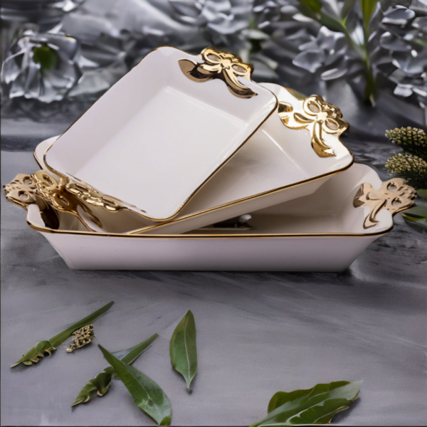 A set of Three white and gold Deep Serving Ceramic dishes on a marble table.
