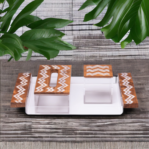a mother of pearl set with zigzag pattern, includes Tray, tissue box and a cube storage box siting on a dark wood table in London.