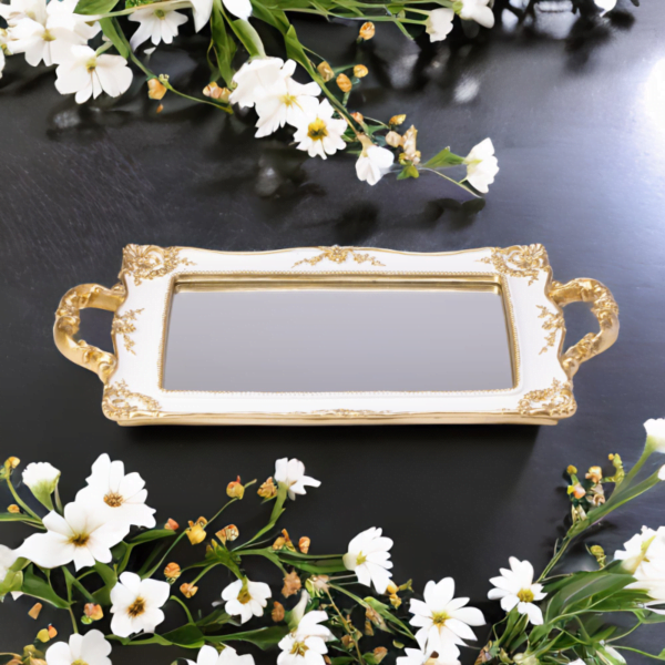A White Mirror tray with gold accents surrounded by white flowers.