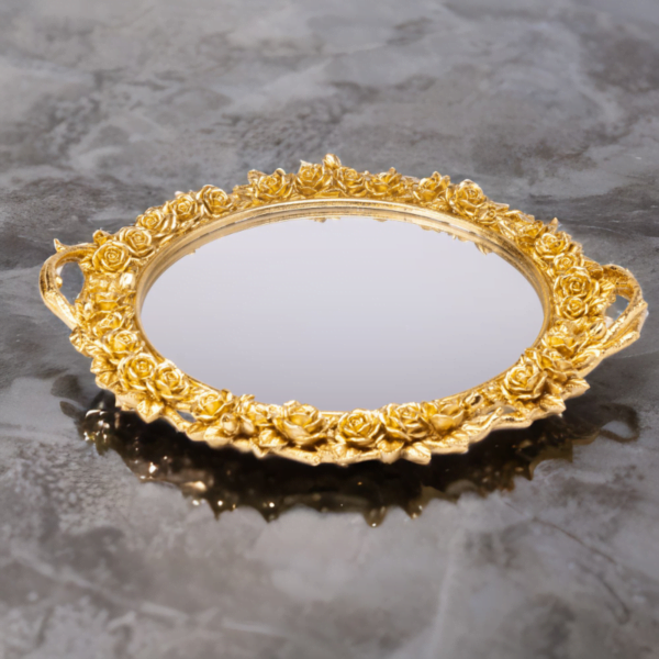 An ornate round gold tray with mirror bottom and gold flower styling.