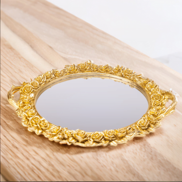 An ornate gold mirror on top of a flower tray.