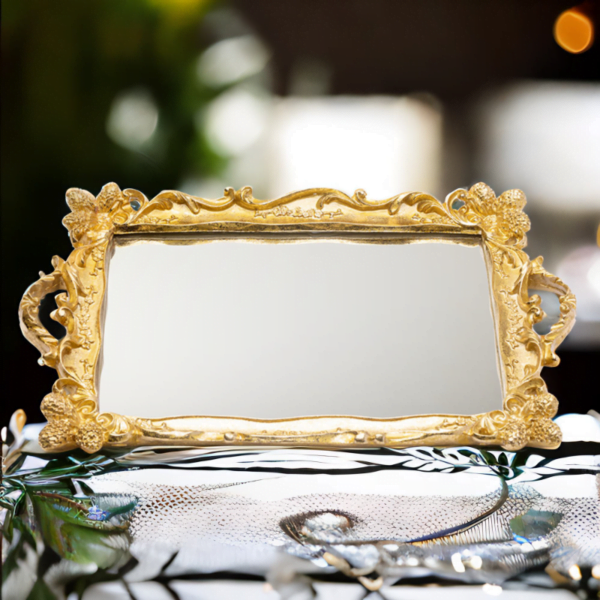 An ornate golden Tray (Rahaf Tray) with mirror bottom on a table.