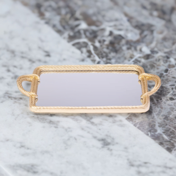 A gold mirror tray with twisted metal styling on a marble top.