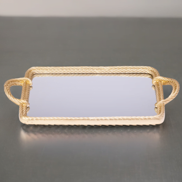 A gold mirror tray with twisted metal styling on a silver surface.