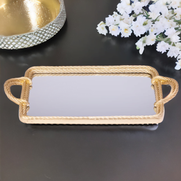 A gold mirror tray with twisted metal styling on a black surface.