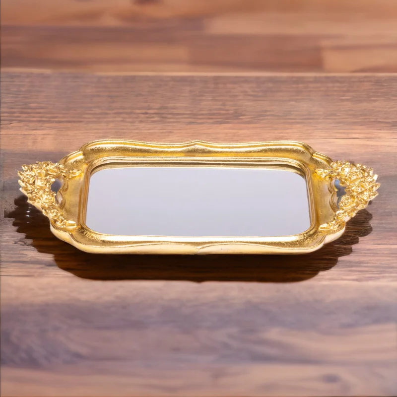 An ornate Gold Fancy Tray with mirror bottom on a wooden table.