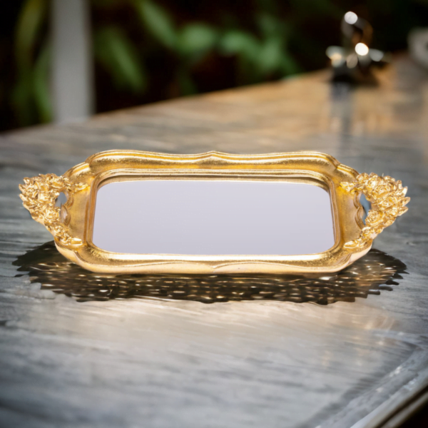 An ornate Gold Fancy Tray with mirror bottom on a table.