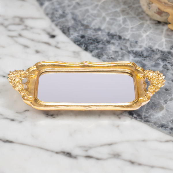 An ornate Gold Fancy Tray with mirror bottom on a marble table.