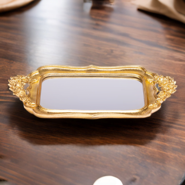 An ornate Gold Fancy Tray with mirror bottom on a wooden table.