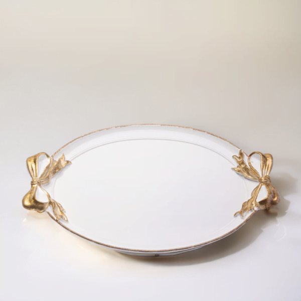 A white tray with gold accents and ribbon handles on a white surface.