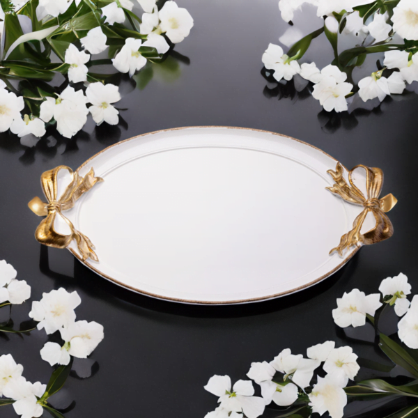 A white tray with gold accents and ribbon handles on a black surface.